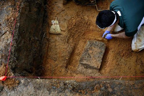 University of South Florida associate professor Christian Wells attempts to cut loose a block of dirt and clay containing skeletal remains i University of South Florida associate professor Christian Wells attempts to cut loose a block of dirt and clay containing skeletal remains i