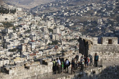 Arab neighbourhoods in East Jerusalem are seen in the background as tourists walk atop a wall surrounding Jerusalem's Old City August 13, 20 Arab neighbourhoods in East Jerusalem are seen in the background as tourists walk atop a wall surrounding Jerusalem's Old City August 13, 20