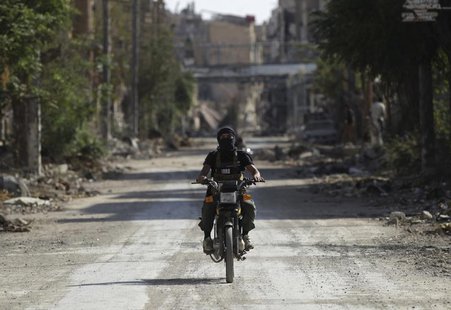 A fighter from the Islamist Syrian rebel group Jabhat al-Nusra rides a motorcycle along a deserted street in Deir al-Zor August 17, 2013. RE A fighter from the Islamist Syrian rebel group Jabhat al-Nusra rides a motorcycle along a deserted street in Deir al-Zor August 17, 2013. RE