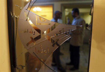 Members of the Muslim Brotherhood speak behind a door with shattered glass at the Muslim Brotherhood headquarters, which was attacked two da Members of the Muslim Brotherhood speak behind a door with shattered glass at the Muslim Brotherhood headquarters, which was attacked two da
