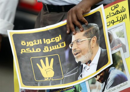 A member of the Muslim Brotherhood and supporter of ousted Egyptian President Mursi holds a poster during a protest named "People Protect th A member of the Muslim Brotherhood and supporter of ousted Egyptian President Mursi holds a poster during a protest named "People Protect th
