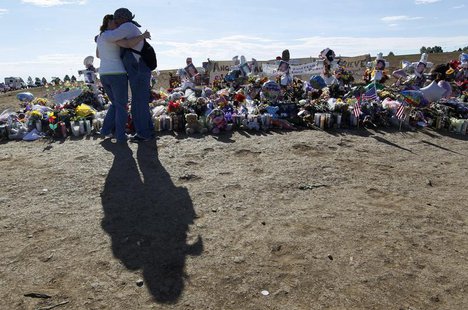 A couple hug early on Sunday morning in front of 12 white crosses at a memorial to those killed in the July 20 theater shootings in Aurora, A couple hug early on Sunday morning in front of 12 white crosses at a memorial to those killed in the July 20 theater shootings in Aurora,