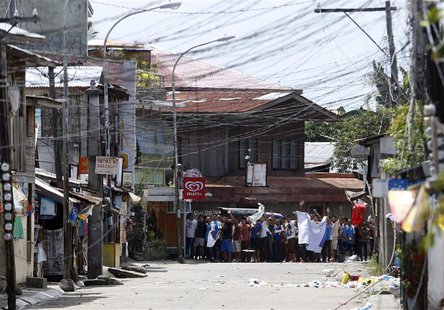 Residents believed to be hostages and used as human shields of Moro National Liberation Front rebels wave white cloth and shout to the gover Residents believed to be hostages and used as human shields of Moro National Liberation Front rebels wave white cloth and shout to the gover