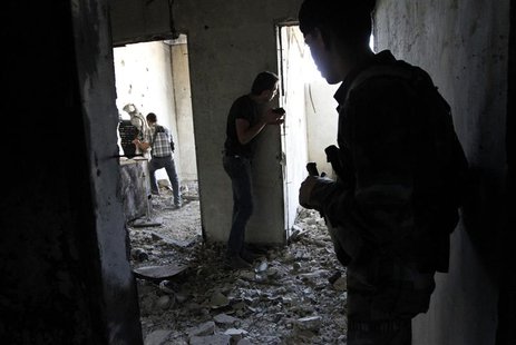 A Free Syrian Army fighter (L) moves through a hole in a wall as his fellow fighter watches while an activist (C) is seen filming inside a h A Free Syrian Army fighter (L) moves through a hole in a wall as his fellow fighter watches while an activist (C) is seen filming inside a h