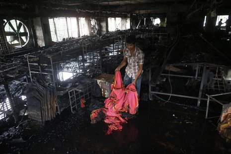 A garment worker inspects a factory belonging to Tung Hai Group, a large garment exporter, after a fire in Dhaka May 9, 2013. REUTERS/Andrew A garment worker inspects a factory belonging to Tung Hai Group, a large garment exporter, after a fire in Dhaka May 9, 2013. REUTERS/Andrew
