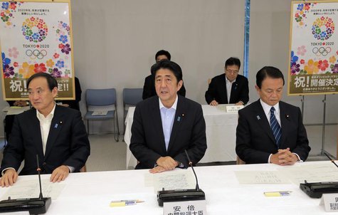 Japan's Prime Minister Shinzo Abe (C), flanked by Chief Cabinet Secretary Yoshihide Suga (L) and Finance Minister Taro Aso, speaks about Tok Japan's Prime Minister Shinzo Abe (C), flanked by Chief Cabinet Secretary Yoshihide Suga (L) and Finance Minister Taro Aso, speaks about Tok