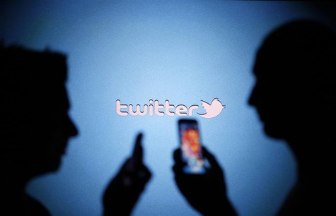 Men are silhouetted against a video screen with a Twitter logo as they pose with Samsung S3 and S4 smartphones in this photo illustration ta Men are silhouetted against a video screen with a Twitter logo as they pose with Samsung S3 and S4 smartphones in this photo illustration ta