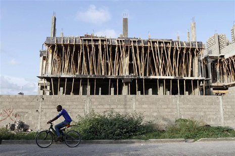 A man rides a bicycle past a building under construction in the Victoria Island district in Nigeria's commercial capital Lagos September 6, A man rides a bicycle past a building under construction in the Victoria Island district in Nigeria's commercial capital Lagos September 6,