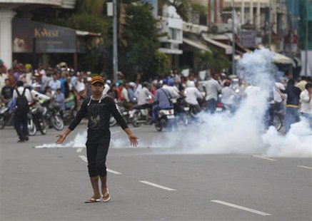 A protester supporting the opposition Cambodia National Rescue Party (CNRP) reacts as police fire tear gas during clashes near the Royal Pal A protester supporting the opposition Cambodia National Rescue Party (CNRP) reacts as police fire tear gas during clashes near the Royal Pal