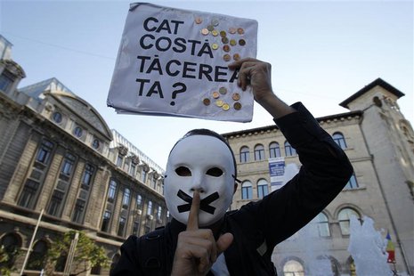 A protester gestures while holding up a placard, which reads: "How much does your silence cost?", during a rally in Bucharest, against plans A protester gestures while holding up a placard, which reads: "How much does your silence cost?", during a rally in Bucharest, against plans