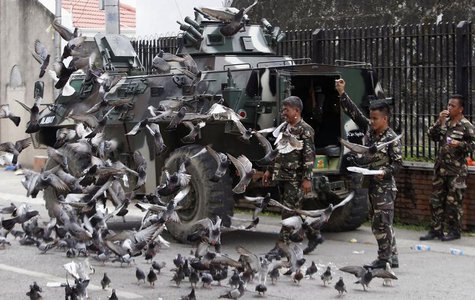 Government soldiers of Task Force Zamboanga feed pigeons with bread crumbs near a military command post during a lull in fighting with Musli Government soldiers of Task Force Zamboanga feed pigeons with bread crumbs near a military command post during a lull in fighting with Musli