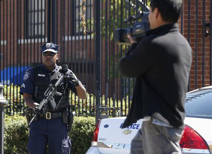 A U.S. Navy policeman (L) lifts his weapon as he warns a cameraman to move away from the main gate at the Washington Navy Yard, September 17 A U.S. Navy policeman (L) lifts his weapon as he warns a cameraman to move away from the main gate at the Washington Navy Yard, September 17