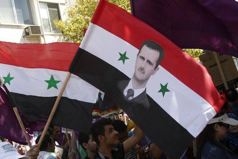 Supporters of Syria's President Bashar al-Assad wave a Syrian national flag depicting Assad's portrait during a rally in front of the parlia Supporters of Syria's President Bashar al-Assad wave a Syrian national flag depicting Assad's portrait during a rally in front of the parlia