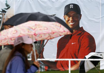 Golf fans walk past a poster of Tiger Woods during a rain delay at the BMW Championship golf tournament at the Conway Farms Golf Club in Lak Golf fans walk past a poster of Tiger Woods during a rain delay at the BMW Championship golf tournament at the Conway Farms Golf Club in Lak