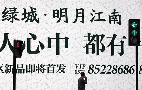 A man talks on his mobile phone as he walks past an advertising billboard outside the Greentown residential construction site in Hangzhou, Z A man talks on his mobile phone as he walks past an advertising billboard outside the Greentown residential construction site in Hangzhou, Z
