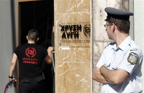 A Greek police officer (R) watches as a member of the Golden Dawn far-right party enters the party's headquarters in Athens September 18, 20 A Greek police officer (R) watches as a member of the Golden Dawn far-right party enters the party's headquarters in Athens September 18, 20