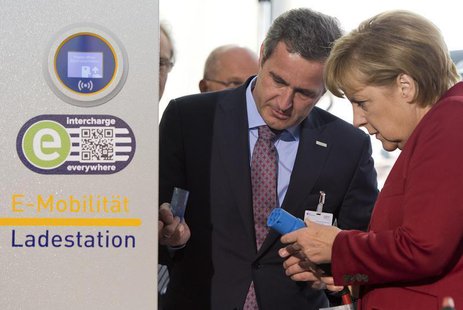 EnBW AG CEO Frank Mastiaux explains the operation of an electric car charging booth to German Chancellor Angela Merkel at the Electric Mobil EnBW AG CEO Frank Mastiaux explains the operation of an electric car charging booth to German Chancellor Angela Merkel at the Electric Mobil