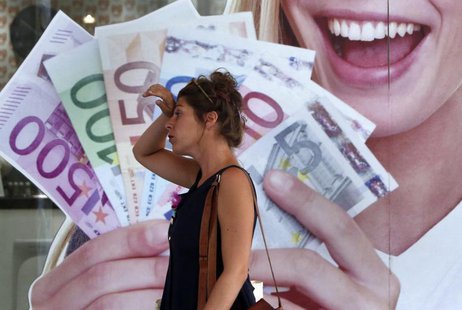 A woman walks by a pawn shop in central Athens August 26, 2013. REUTERS/John Kolesidis A woman walks by a pawn shop in central Athens August 26, 2013. REUTERS/John Kolesidis