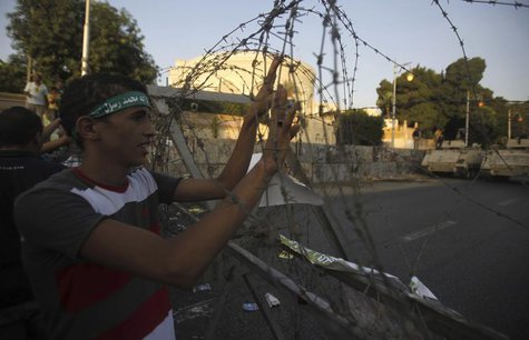 A member of the Muslim Brotherhood and supporter of ousted Egyptian President Mohamed Mursi holds onto barbed wire as he shouts slogans agai A member of the Muslim Brotherhood and supporter of ousted Egyptian President Mohamed Mursi holds onto barbed wire as he shouts slogans agai