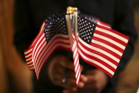 A woman holds a cluster of U.S. flags during a U.S. Citizenship and Immigration Services naturalization ceremony in Oakland, California Augu A woman holds a cluster of U.S. flags during a U.S. Citizenship and Immigration Services naturalization ceremony in Oakland, California Augu