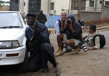 A policeman and photographers take cover after hearing gun shots near the Westgate shopping centre in Nairobi September 23, 2013. REUTERS/Ka A policeman and photographers take cover after hearing gun shots near the Westgate shopping centre in Nairobi September 23, 2013. REUTERS/Ka
