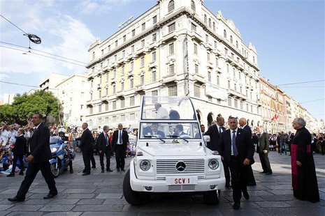 Bodyguards escort Pope Francis as the faithful welcome his arrival in his Pope-mobile for a meeting with youths in Largo Carlo Felice in Cag Bodyguards escort Pope Francis as the faithful welcome his arrival in his Pope-mobile for a meeting with youths in Largo Carlo Felice in Cag