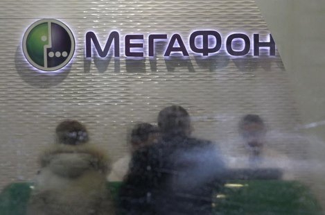 Customers and staff are seen through the partially cleaned window of a Megafon shop in Moscow November 28, 2012. REUTERS/Sergei Karpukhin Customers and staff are seen through the partially cleaned window of a Megafon shop in Moscow November 28, 2012. REUTERS/Sergei Karpukhin