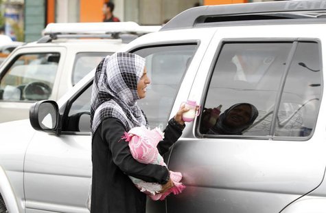 A Syrian refugee holding a child begs on a main street in Sanaa September 19, 2013. REUTERS/Mohamed al-Sayaghi A Syrian refugee holding a child begs on a main street in Sanaa September 19, 2013. REUTERS/Mohamed al-Sayaghi