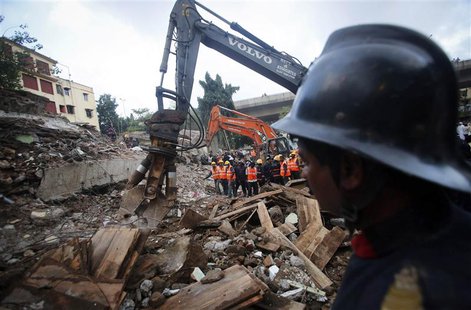 Rescue crew members watch as others use excavators to scour the debris for survivors at the site of a collapsed residential building in Mumb Rescue crew members watch as others use excavators to scour the debris for survivors at the site of a collapsed residential building in Mumb