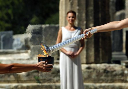 Greek actress Ino Menegaki (R), playing the role of High Priestess, passes the Olympic Flame to a priestess holding a cauldron (L) during a Greek actress Ino Menegaki (R), playing the role of High Priestess, passes the Olympic Flame to a priestess holding a cauldron (L) during a