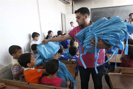 A man distributes bags donated from UNICEF to young students in Raqqa, eastern Syria September 29, 2013. The distribution of around 60,000 b A man distributes bags donated from UNICEF to young students in Raqqa, eastern Syria September 29, 2013. The distribution of around 60,000 b