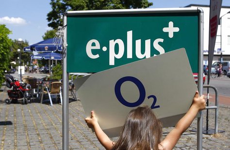 A young girl holds up the logo of O2 Deutschland, the German daughter of Spain's Telefonica, close to the E-Plus logo in front of an E-Plus A young girl holds up the logo of O2 Deutschland, the German daughter of Spain's Telefonica, close to the E-Plus logo in front of an E-Plus