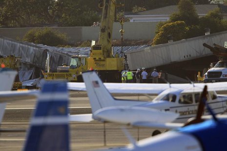 Workers prepare to use cranes to extract a twin-engine Cessna Citation 525A aircraft from inside a collapsed hangar which it slammed into, b Workers prepare to use cranes to extract a twin-engine Cessna Citation 525A aircraft from inside a collapsed hangar which it slammed into, b