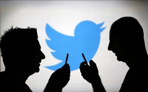 Men are silhouetted against a video screen with a Twitter logo as he poses with a Samsung S4 smartphone in this photo illustration taken in Men are silhouetted against a video screen with a Twitter logo as he poses with a Samsung S4 smartphone in this photo illustration taken in