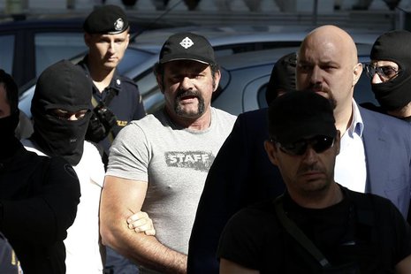 Extreme-right Golden Dawn party lawmaker Yannis Lagos (C) is escorted by anti-terrorism police officers after he was ordered to be kept in d Extreme-right Golden Dawn party lawmaker Yannis Lagos (C) is escorted by anti-terrorism police officers after he was ordered to be kept in d