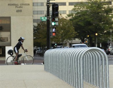 A lone cyclist waits for a traffic signal near empty bicycle racks in the Federal Center Plaza area during day three of the U.S. government A lone cyclist waits for a traffic signal near empty bicycle racks in the Federal Center Plaza area during day three of the U.S. government