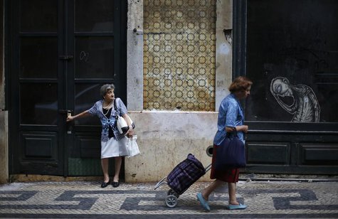 A woman pulls a shopping bag as another waits for a bus in downtown Lisbon July 11, 2013. REUTERS/Rafael Marchante A woman pulls a shopping bag as another waits for a bus in downtown Lisbon July 11, 2013. REUTERS/Rafael Marchante