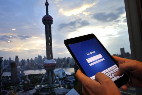 In this photo illustration, a man holds an iPad with a Facebook application in an office building at the Pudong financial district in Shangh In this photo illustration, a man holds an iPad with a Facebook application in an office building at the Pudong financial district in Shangh