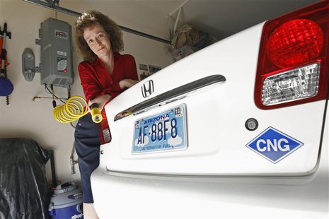 Connie Jones with her 2003 natural gas powered Honda Civic and natural gas home refueling station located on the garage wall of her home in Connie Jones with her 2003 natural gas powered Honda Civic and natural gas home refueling station located on the garage wall of her home in