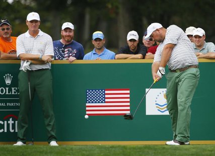 International team member Brendon de Jonge of Zimbabwe (R) is watched by teammate Ernie Els of South Africa as he tees off the ninth hole du International team member Brendon de Jonge of Zimbabwe (R) is watched by teammate Ernie Els of South Africa as he tees off the ninth hole du