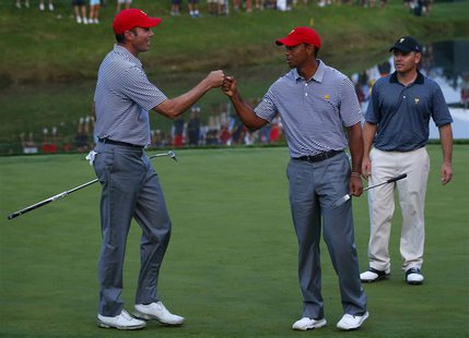 U.S. teammates Matt Kuchar (L) and Tiger Woods celebrate winning the 12th hole as International team member Louis Oosthuizen of South Africa U.S. teammates Matt Kuchar (L) and Tiger Woods celebrate winning the 12th hole as International team member Louis Oosthuizen of South Africa