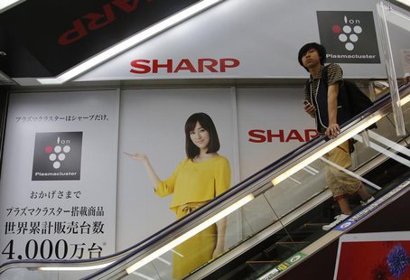 A man rides an escalator past Japanese display maker Sharp Corp's advertisements at an electronics retail store in Tokyo May 14, 2013. REUTE A man rides an escalator past Japanese display maker Sharp Corp's advertisements at an electronics retail store in Tokyo May 14, 2013. REUTE