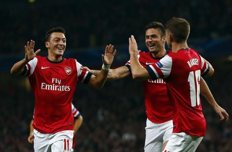 Arsenal's Mesut Ozil (L) celebrates with teammates Olivier Giroud and Aaron Ramsey (R) after scoring a goal against Napoli during their Cham Arsenal's Mesut Ozil (L) celebrates with teammates Olivier Giroud and Aaron Ramsey (R) after scoring a goal against Napoli during their Cham