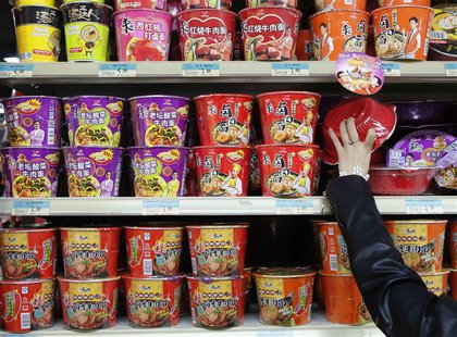 A woman chooses a cup noodle from a shelf displaying cup noodles from Uni-President China (top and middle) and Tingyi (bottom) at a supermar A woman chooses a cup noodle from a shelf displaying cup noodles from Uni-President China (top and middle) and Tingyi (bottom) at a supermar