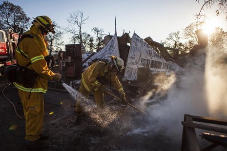 Shasta County firefighters Zach Lacy (L) and Bob Baker spray water on a home burnt by the Clover Fire in Happy Valley, California September Shasta County firefighters Zach Lacy (L) and Bob Baker spray water on a home burnt by the Clover Fire in Happy Valley, California September