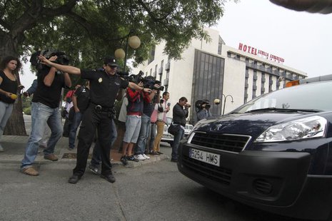 A policeman blocks cameramen as the body of Maria de Villota, former Marussia Formula One test driver, is taken away after she was found dea A policeman blocks cameramen as the body of Maria de Villota, former Marussia Formula One test driver, is taken away after she was found dea