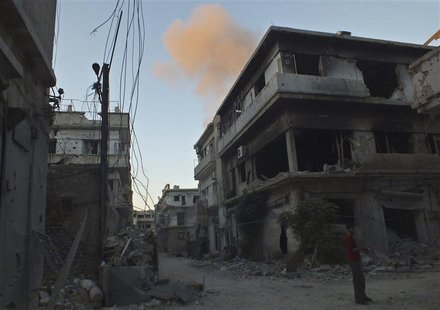 A man stands in front of buildings damaged by what activists said was shelling by forces loyal to Syria's President Bashar al-Assad, as smok A man stands in front of buildings damaged by what activists said was shelling by forces loyal to Syria's President Bashar al-Assad, as smok