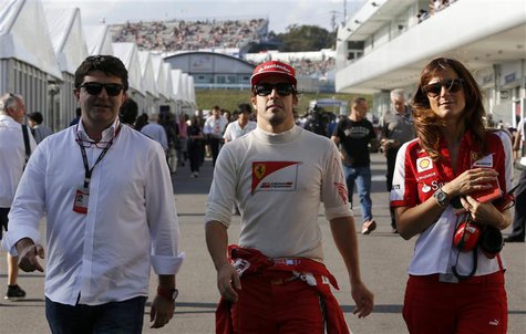 Ferrari Formula One driver Fernando Alonso (C) of Spain walks in the paddock with his agent Luis Garcia Abad (L) and his press officer Rober Ferrari Formula One driver Fernando Alonso (C) of Spain walks in the paddock with his agent Luis Garcia Abad (L) and his press officer Rober