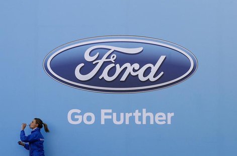 A woman has a drink as she walks past a logo of carmaker Ford at the entrance to a media event for the launch of a concept car in Sydney Aug A woman has a drink as she walks past a logo of carmaker Ford at the entrance to a media event for the launch of a concept car in Sydney Aug