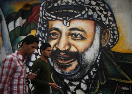 Palestinians walk past a mural depicting late Palestinian leader Yasser Arafat in Gaza City November 27, 2012. REUTERS/Suhaib Salem Palestinians walk past a mural depicting late Palestinian leader Yasser Arafat in Gaza City November 27, 2012. REUTERS/Suhaib Salem
